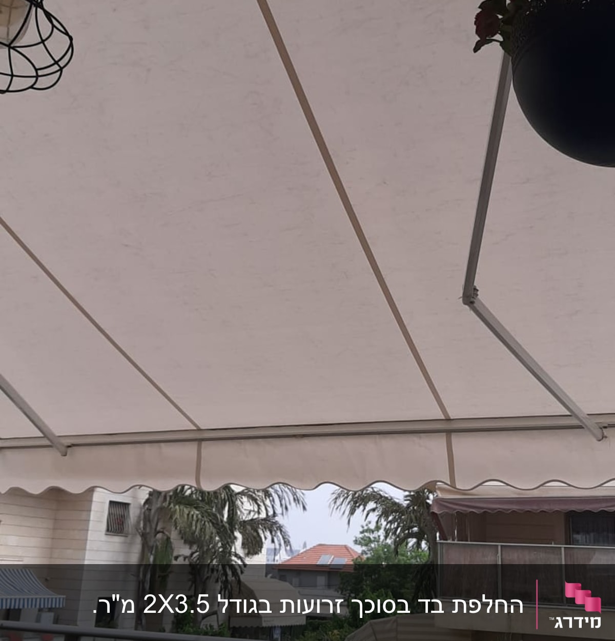סוכך לבן מתוח מעל מרפסת עם שולחן וכיסאות